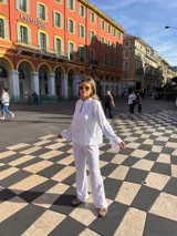 Camisa blanca de broderie con cuello camisero, mangas largas y cierre frontal con botones.