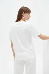 Remera blanca de manga corta y cuello redondo, confeccionada en algodón, con un diseño holgado y estampado frontal de estrella roja con textura y detalles de estrellas pequeñas.