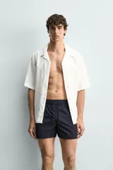 Short de baño de color azul marino, confeccionado en tejido técnico, con cintura elástica ajustable mediante cordón, bolsillos laterales y detalle de bolsillo trasero.
