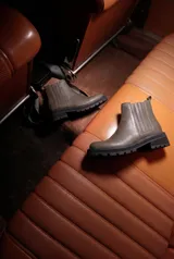 Bota tipo chelsea de cuero color gris topo, con paneles laterales elásticos y suela track negra de goma con plataforma.
