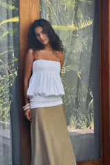 Vestido midi de diseño strapless con escote recto. Presenta un cuerpo superior blanco con textura fruncida y una falda inferior en tono beige con caída fluida.