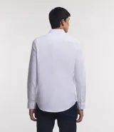 Camisa de vestir blanca de algodón con textura maquinetada, cuello camisero y mangas largas.
