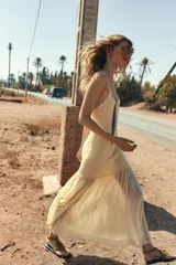 Vestido largo color amarillo pálido, de breteles finos cruzados en la espalda y falda plisada.