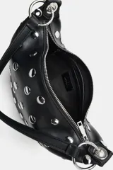 Bolso de mano tipo saca con diseño redondeado, confeccionado en material sintético color marrón oscuro. Presenta múltiples tachas metálicas doradas distribuidas por toda la superficie y un asa superior sujeta por anillas metálicas doradas. Cuenta con cierre superior mediante cremallera metálica.