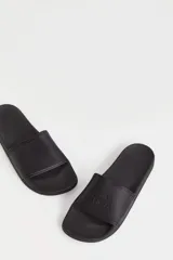 Ojotas tipo slide marca Caro Cuore, color negro, con banda ancha superior que presenta el logo de la marca grabado en relieve.
