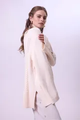 Sweater de punto color bordó con cuello alto y diseño de trenzas en el frente y las mangas. Presenta un corte holgado y largo, con puños y ruedo acanalados.