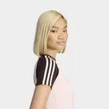 Remera Adidas de ajuste ceñido, color rosa claro con mangas y cuello en color marrón oscuro. Presenta las icónicas tres rayas de la marca en las mangas y el logo del trébol bordado en el pecho.