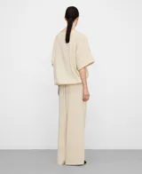 Blusa globo amplia de color beige con escote barco y manga corta japonesa. Presenta bajo abullonado con elástico interior.