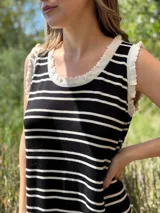 Vestido largo de punto a rayas horizontales negras y blancas, sin mangas, con cuello redondo y volados blancos en cuello y sisas.