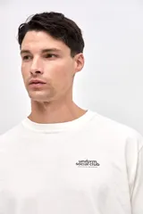 Remera manga larga de algodón lavado con textura suave, color gris oscuro, con estampado pequeño en el pecho y estampado en la manga.