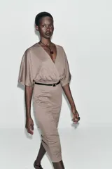 Vestido midi de tejido piqué en color marrón oscuro jaspeado, con escote en pico cruzado y mangas cortas. Presenta detalle de frunces en la cintura y un cinturón integrado con hebilla metálica a contraste.