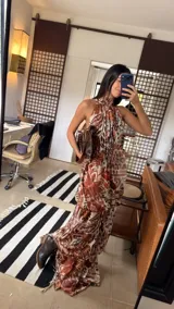 Vestido largo tipo globo con cuello halter y espalda descubierta, confeccionado en tela fluida con estampado botánico y geométrico en tonos tierra.