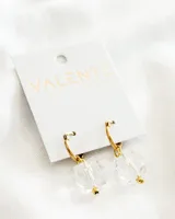 Aros colgantes dorados con dije de cristal transparente facetado y detalles dorados.