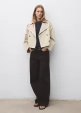 Chaqueta corta tipo trench con cuello de solapa y cierre de doble botonadura. Presenta diseño recto, manga larga y forro interior.