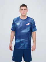 Remera deportiva Umbro del Club Nacional de Football, modelo Press para hombre. Diseño en tonos de azul con patrón estampado tipo desteñido, cuello redondo y mangas cortas. Incluye el logo de Umbro y el escudo del club en el frente.