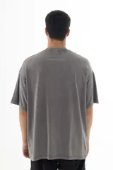 Remera gris con efecto acid wash, corte holgado y estampa pequeña en el pecho con diseño abstracto en color fucsia.
