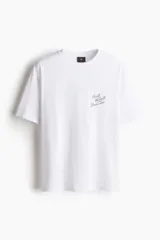 Remera de algodón blanca con cuello redondo y hombros caídos. Presenta un pequeño estampado tipográfico en el pecho con la frase 'Puerto Vallarta Beach Bar'.