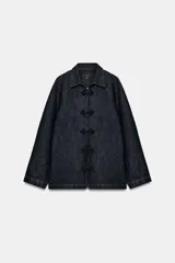 Chaqueta de denim azul oscuro con cuello solapa, manga larga y cierre frontal mediante alamares decorativos de estilo oriental.
