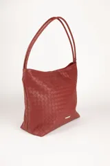 Bolso tipo shopper de símil cuero trenzado color marrón oscuro, con asas fijas centrales y gran compartimiento interior con tres bolsillos adicionales.