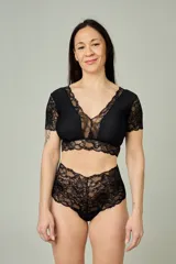 Conjunto de lencería negro compuesto por un bralette de lycra y microtul con detalles de encaje en escote, bajo busto y mangas cortas, y una bombacha hipster de tiro alto confeccionada íntegramente en encaje.