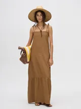 Vestido midi de denim color marrón, con corte holgado, breteles finos con lazos ajustables y detalle de volado en el ruedo.