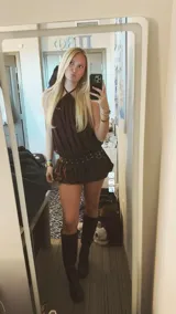 Vestido corto marrón con cuello halter y falda globo con cinturón con ojales y hebilla metálica.