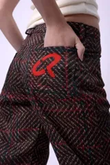 Pantalón de corte recto y largo al tobillo, con estampado de espiga en tonos oscuros y líneas rojas. Presenta tiro medio y cierre frontal.