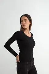 Sweater de punto fino en color negro, con cuello redondo y mangas largas, de corte ajustado al cuerpo.