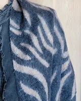 Bufanda de gran tamaño con estampado animal print en tonos negro y beige, con terminación de flecos en los extremos.