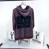 Canguro oversize bordó con efecto lavado, capucha con cordones ajustables y bolsillo tipo canguro. Estampa en la espalda con el logo de la marca Duxon Jeans y el texto "Est. 1982 London".
