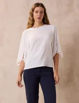 Blusa de gasa con estampado geométrico en tonos negro, gris y celeste. Tiene cuello redondo y mangas 3/4 amplias con abertura y botón.