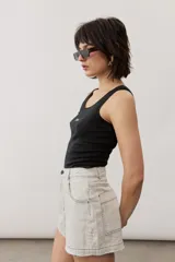 Short gris claro de tiro alto con costuras pespunteadas en contraste y bolsillos traseros amplios. Presenta una etiqueta de cuero rojo en la parte posterior de la cintura.
