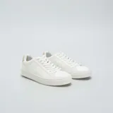 Zapatillas bajas blancas de cuero sintético con cordones y detalle en color beige en el talón.