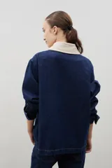 Campera de jean azul oscuro con cuello de pana en color crema. Presenta cierre frontal metálico, bolsillo con cierre en el pecho y bolsillos laterales. Diseño de corte holgado con mangas largas.