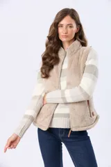 Chaleco de sherpa con cierre frontal, cuello alto y bolsillos laterales. Presenta detalles en cuero sintético en los tiradores de los cierres.