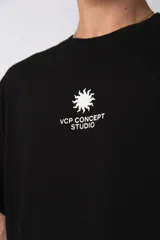 Remera de corte oversize color verde oliva, confeccionada en algodón premium. Presenta un diseño minimalista con un pequeño estampado frontal de un sol y el texto VCP Concept Studio, y una gráfica protagonista en la espalda.