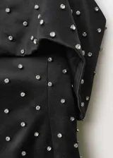 Vestido corto de fiesta en tejido satinado negro, con diseño entallado y escote palabra de honor con solapa vuelta. Presenta apliques decorativos brillantes distribuidos por toda la prenda y cierre de cremallera en la parte posterior.