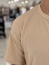 Remera oversize de tejido de punto color beige, de manga corta y cuello redondo.