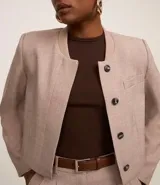 Blusa color beige de mangas cortas, confeccionada en tejido rib con textura acanalada y cuello redondo.