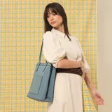Cartera tipo tote de estructura vertical, con doble asa larga para llevar al hombro y bolsillo frontal exterior.