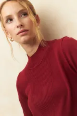 Polera color borgoña de tejido de punto con cuello alto y mangas largas.