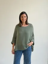 Sweater de punto calado en color verde seco, con escote redondo, mangas largas anchas y diseño holgado.