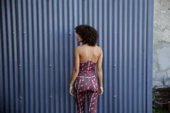 Top deportivo color borgoña con estampado abstracto en tonos rosa y beige, con tirantes finos y espalda deportiva.