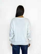 Buzo de punto color blanco, de corte recto y holgado, con cuello redondo y puños y ruedo acanalados.