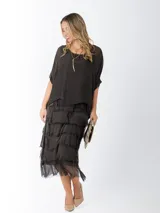 Vestido midi de seda italiana color negro, diseño dos en uno con capa superior de calce amplio, falda con volados y forro interior de algodón elastizado.