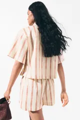 Short de popelina de algodón de tiro alto con cintura fruncida y bolsillos laterales discretos, de bajo levemente redondeado. Presenta un diseño de rayas verticales sobre base beige.
