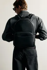Mochila negra con acabado texturizado y detalle metálico. Cuenta con compartimento principal con cierre de cremallera, bolsillo frontal con cierre, asa de mano superior y correas ajustables para los hombros.