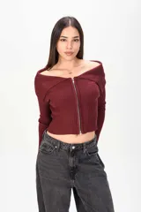 Sweater corto de tejido acanalado en color bordó, con cuello tipo off-shoulder solapado y cierre frontal completo con cremallera.