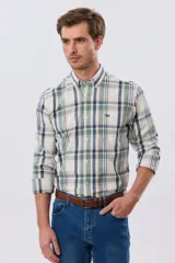 Camisa de manga larga de calce slim, con diseño a cuadros en tonos azul oscuro, verde y blanco. Presenta cuello camisero con botones y bolsillo ojal en el pecho con detalle bordado.