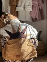 Buzo de corderito con diseño de atardecer en la espalda, combinando colores blanco y camel. Presenta cuello alto con cierre y mangas largas.